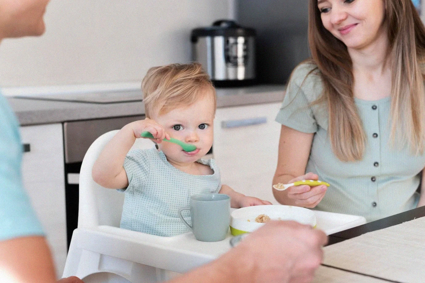 Mother feeding adorable baby with a spoon, introducing nourishing baby formula.