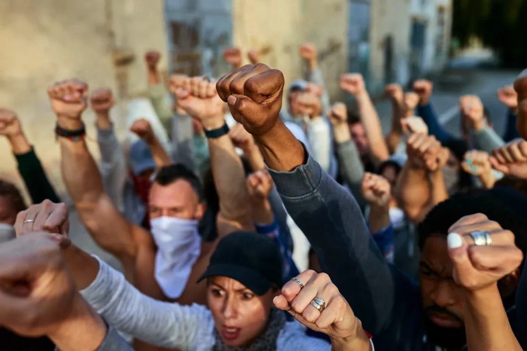 A crowd of people with raised fists demanding their rights. They are part of the Camp Lejeune Mass Tort, a legal battle against the U.S. government for exposing them to toxic water.